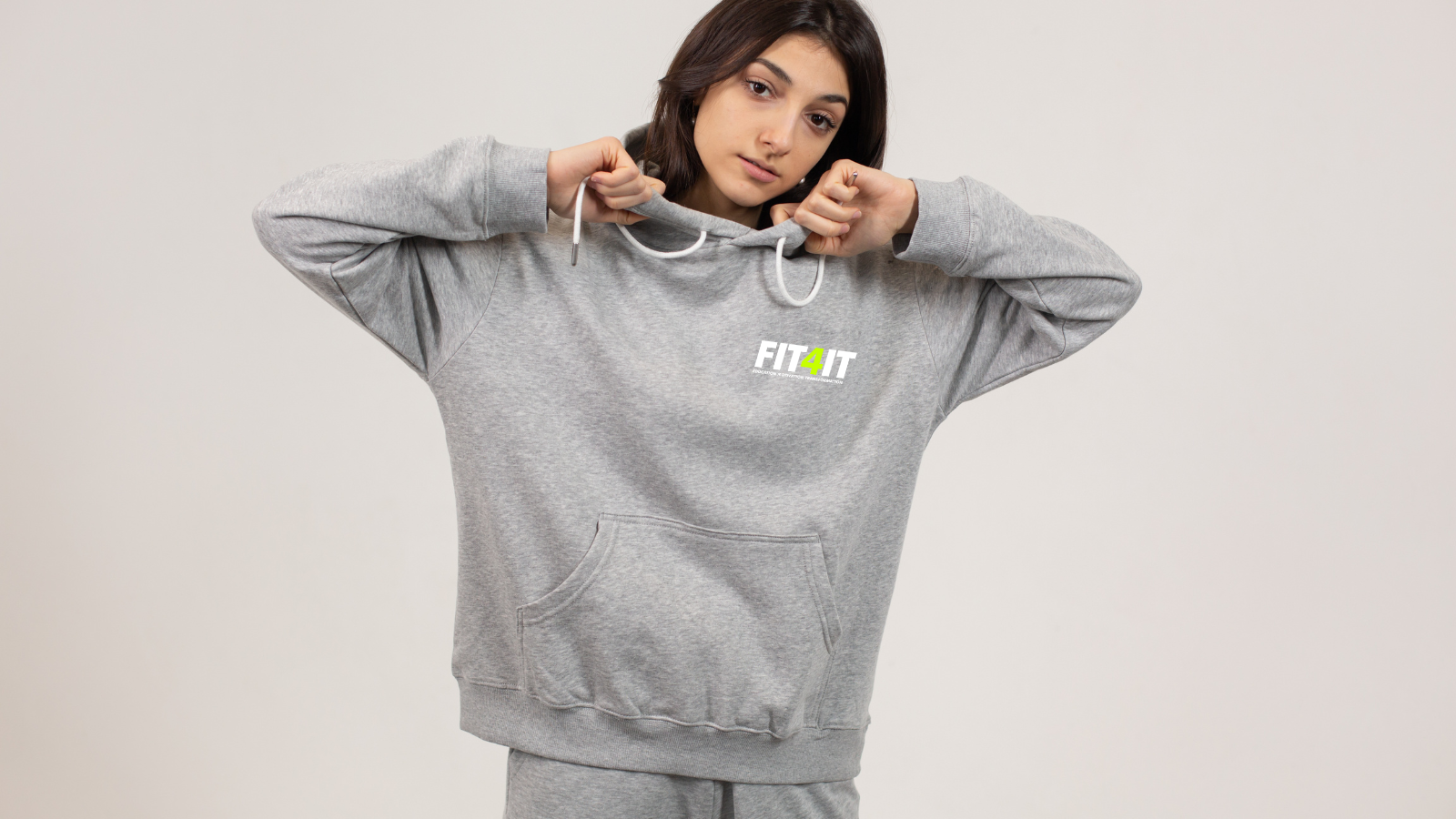 A woman is wearing a grey hoodie and sweatpants.