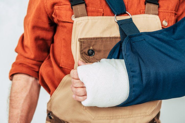 Repairman with broken arm and bandage on white background