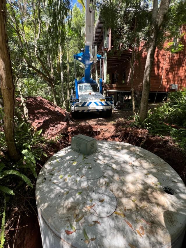 A Large Concrete Cylinder Is Sitting In The Middle Of A Forest Next To A Crane — Etosha Plumbing & Gasfitting In Bangalow, NSW