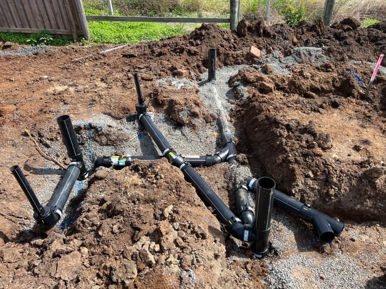 A Bunch Of Pipes Are Laying In The Dirt — Etosha Plumbing & Gasfitting In Alstonville, NSW