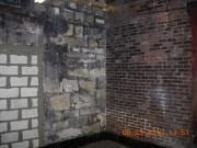 Dim brick wall corner with patches of white cinder blocks and dark stains