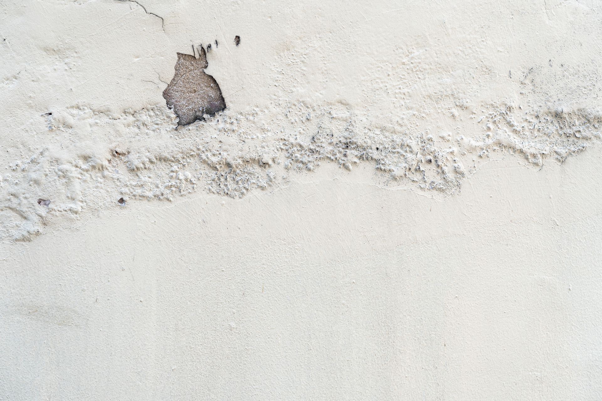 Peeling white wall with a small damaged patch near the top left. Peeling white wall with a small damaged patch near the top left.