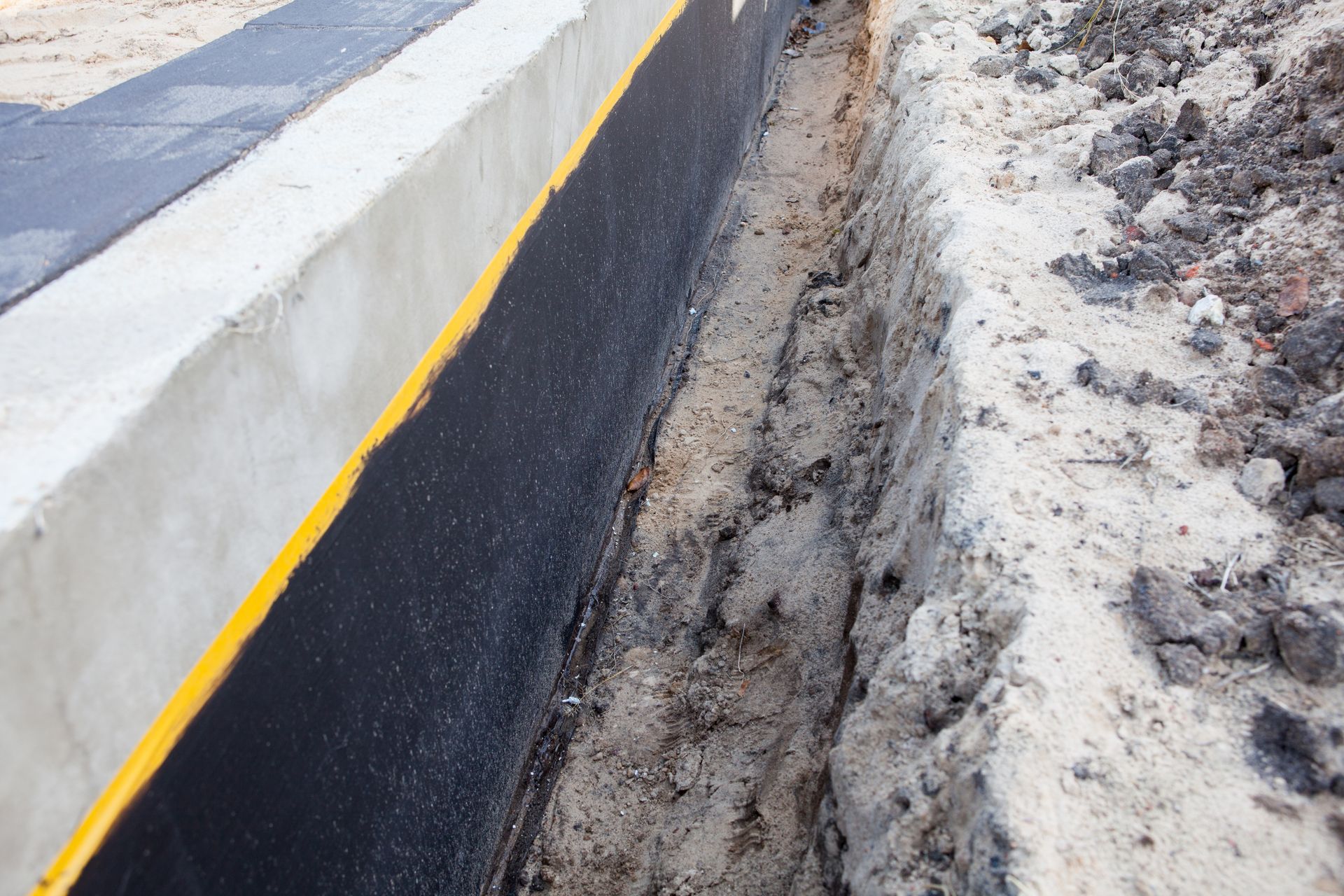 Freshly paved road edge with a white curb and yellow line beside muddy snowbanks