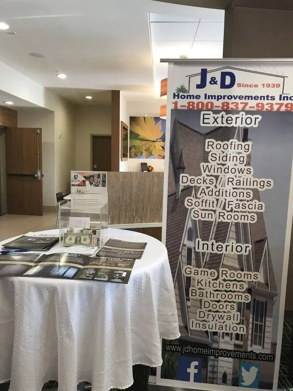 J&D contractor booth with service banner, brochure table, and exterior/interior renovation signs