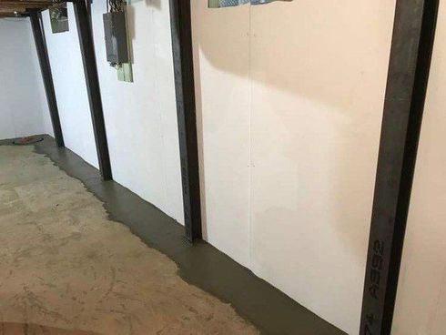 Narrow indoor hallway with white walls, dark door frames, and a concrete floor. Narrow indoor hallway with white walls, dark door frames, and a concrete floor.