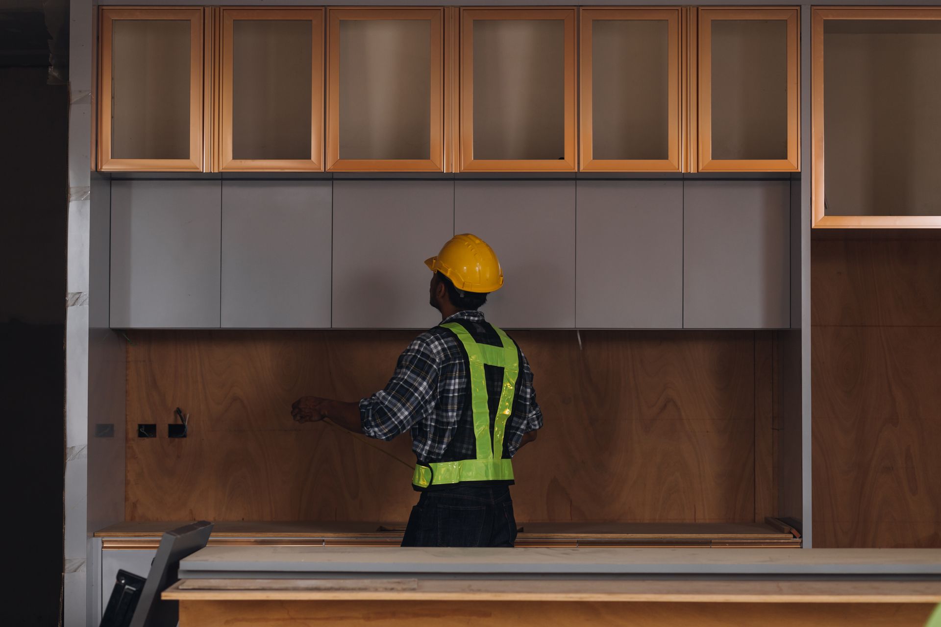 Two men are standing in an empty room with a tape measure.