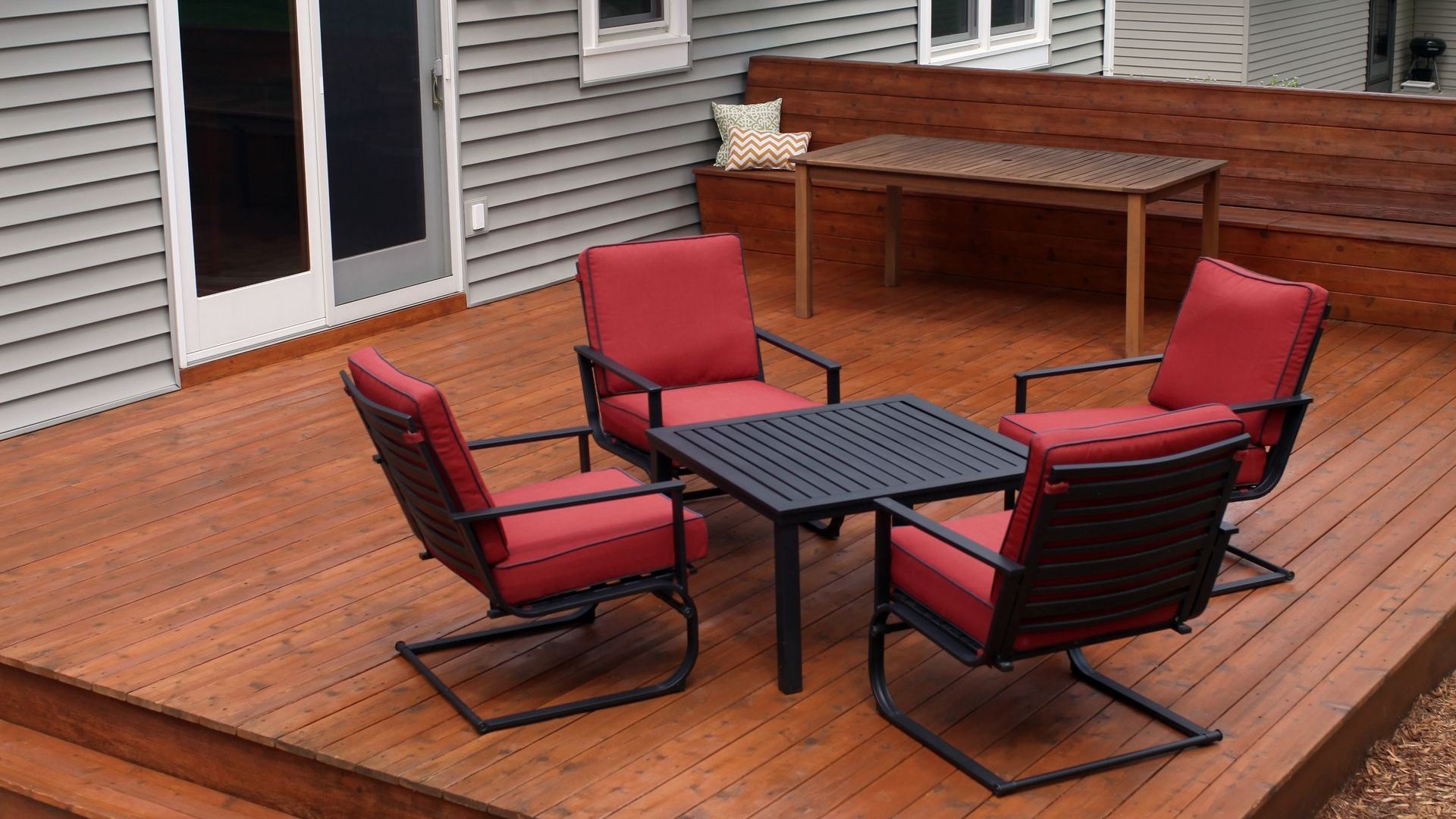 A wooden deck with chairs and a table in front of a house