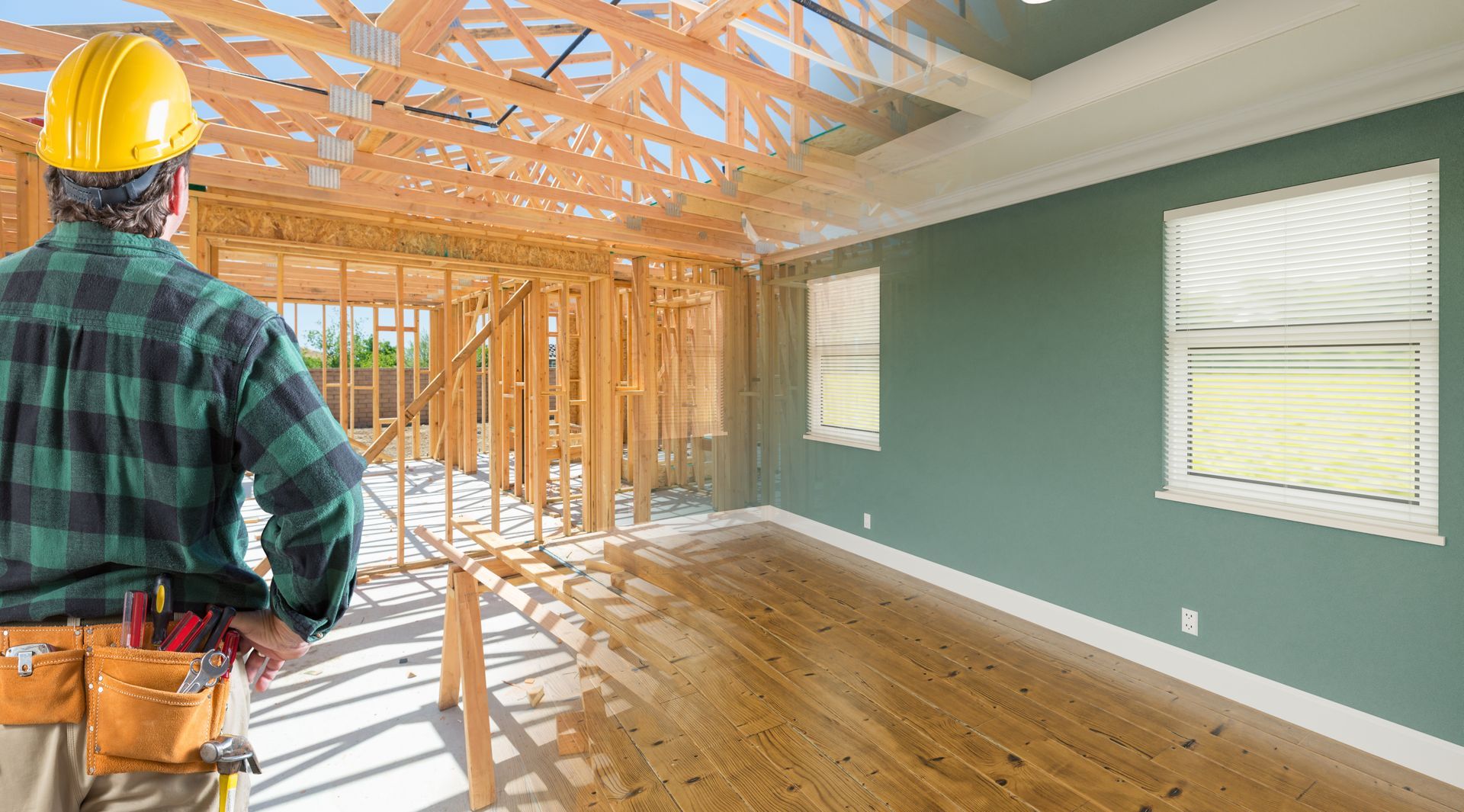 A construction worker is looking at a house under construction.