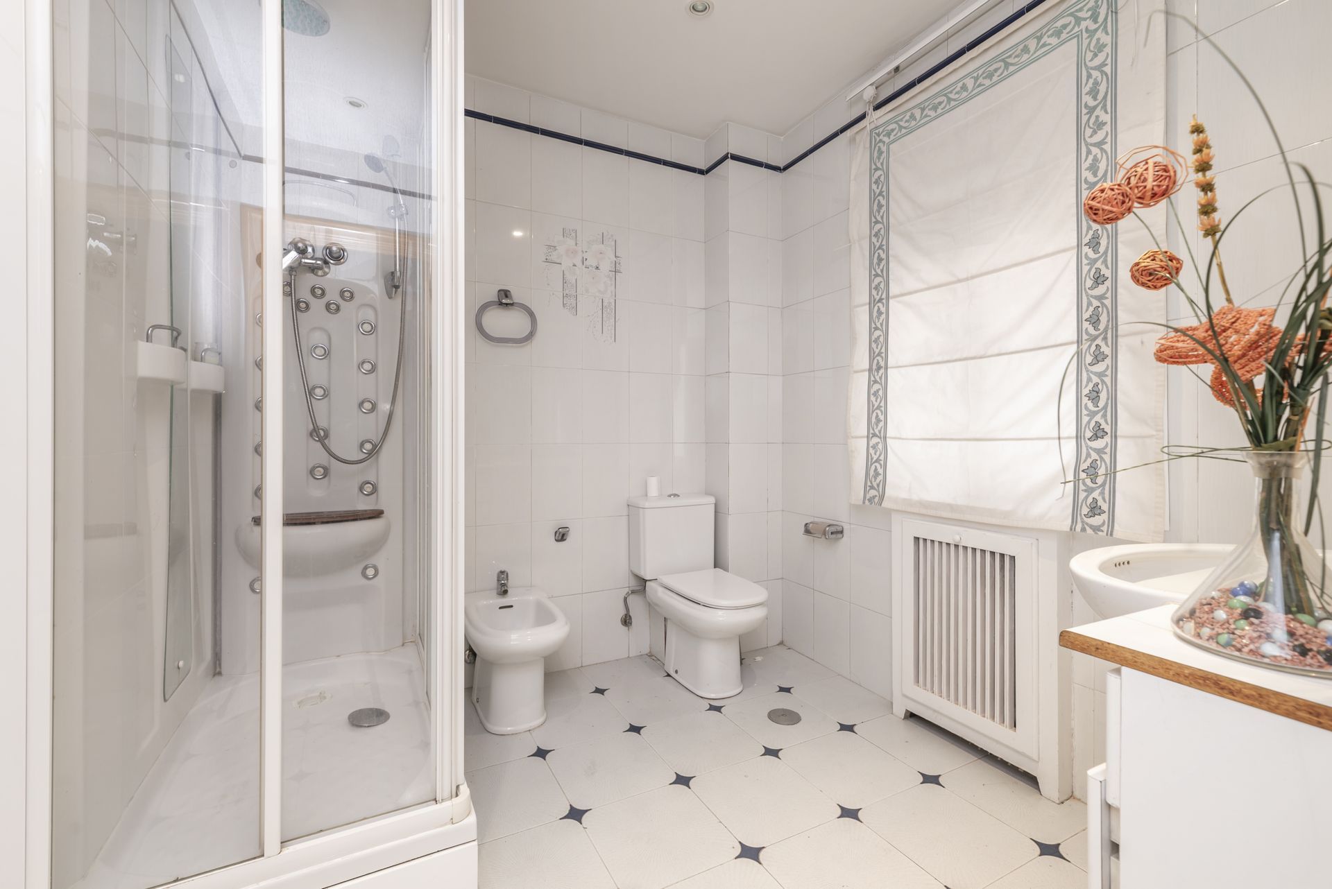 A bathroom with a toilet , bidet , sink and shower.