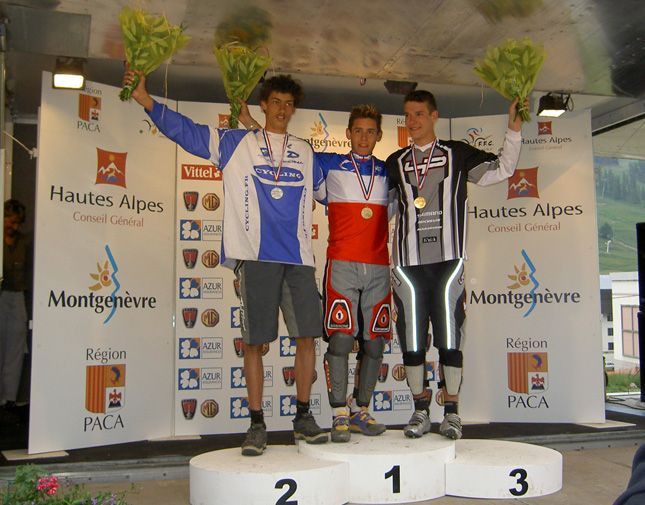 A group of young men are standing on a podium holding flowers in front of a wall that says hautes alpes