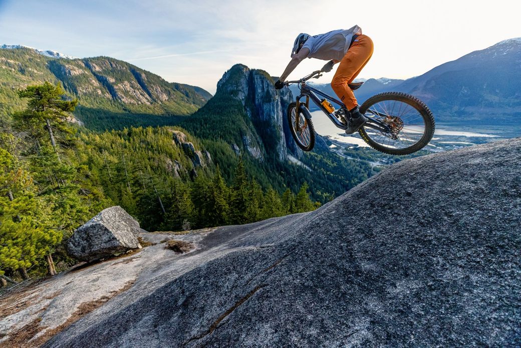 A person is riding a bike on a trail in the woods.