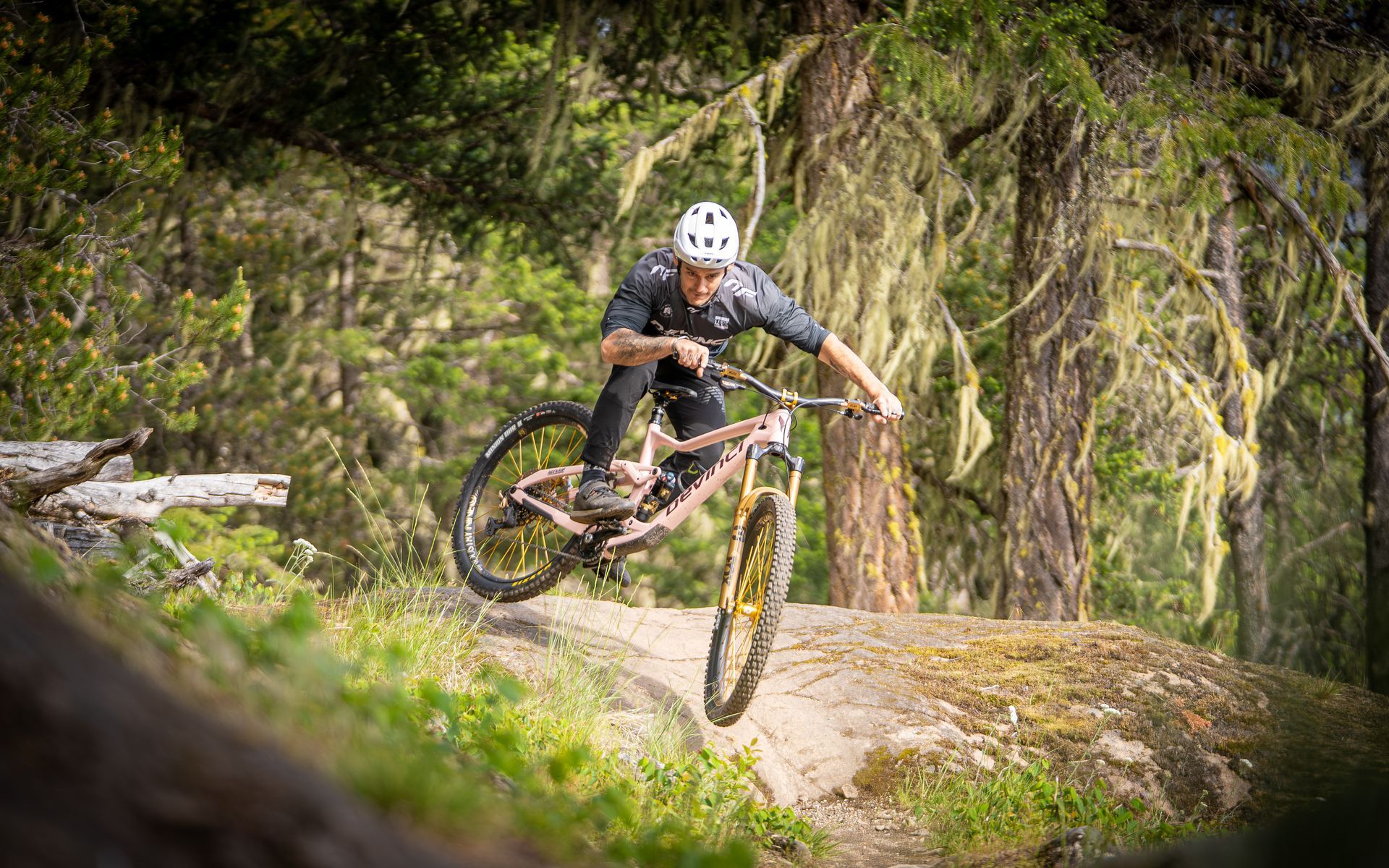 A man is riding a mountain bike down a trail in the woods.