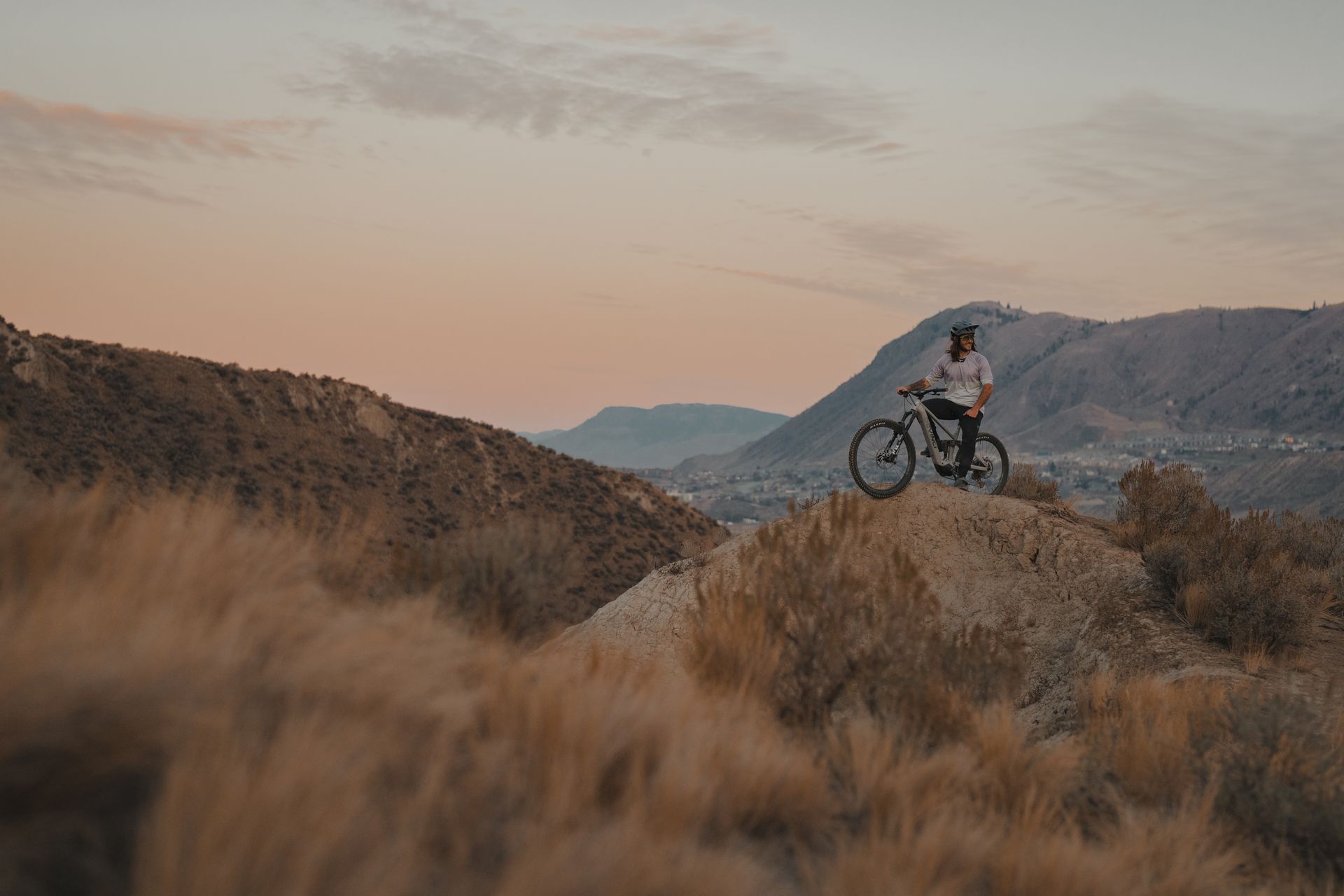 A person is standing on top of a mountain with a bicycle.