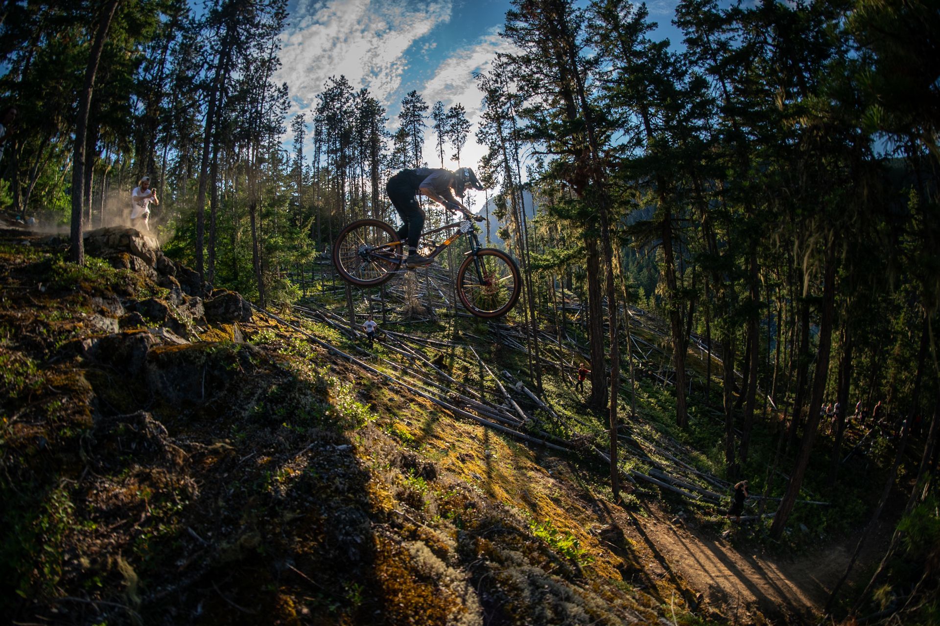 A man is riding a mountain bike down a trail in the woods.