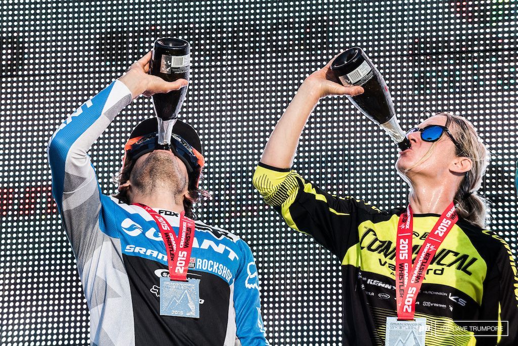 A man and a woman are drinking champagne from bottles.