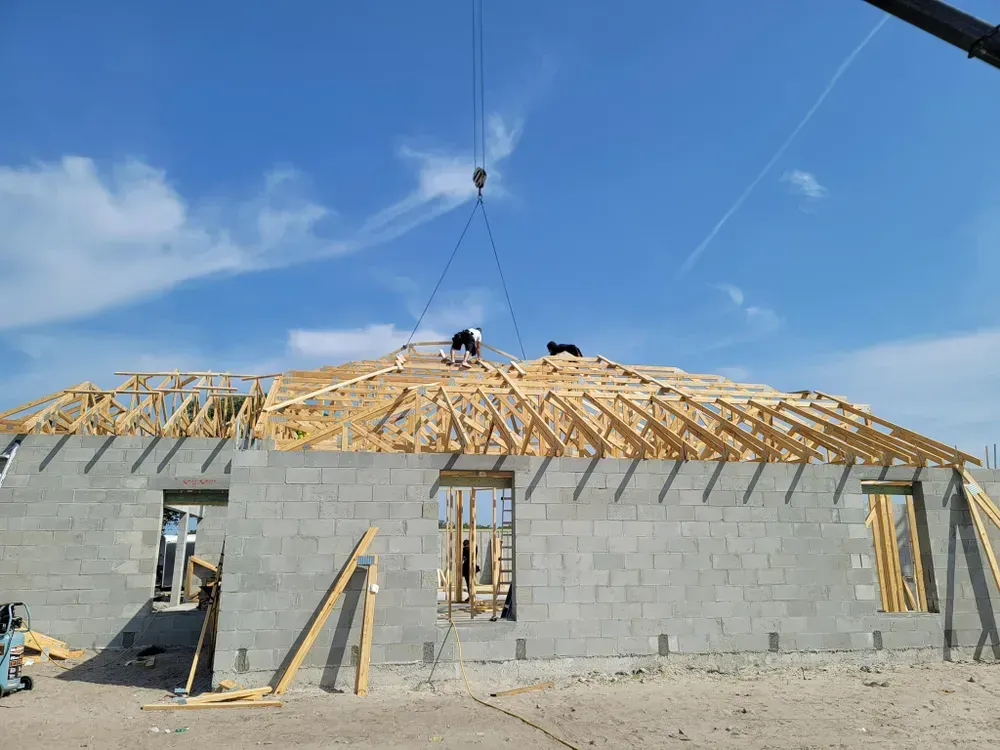 A crane is lifting a wooden structure on top of a building under construction.