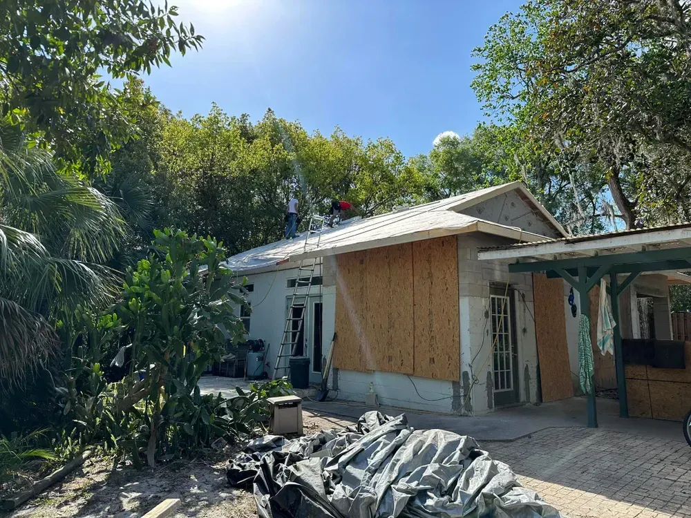 A house that is being remodeled with a lot of trees in the background.