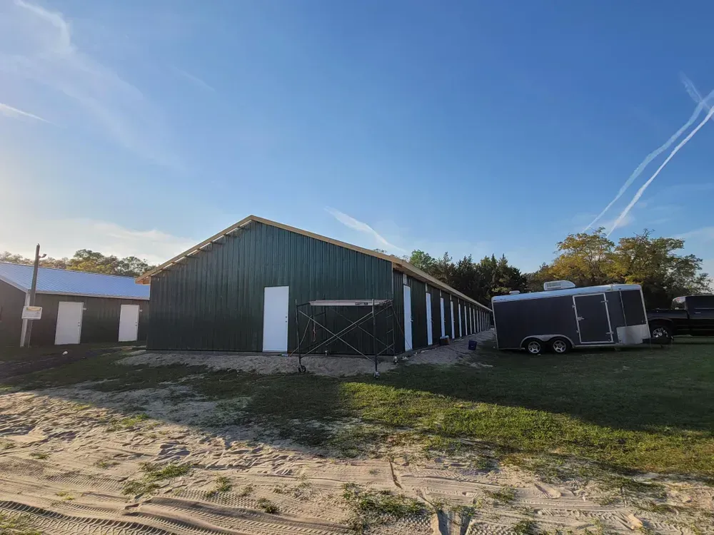 A green building with a trailer parked in front of it.