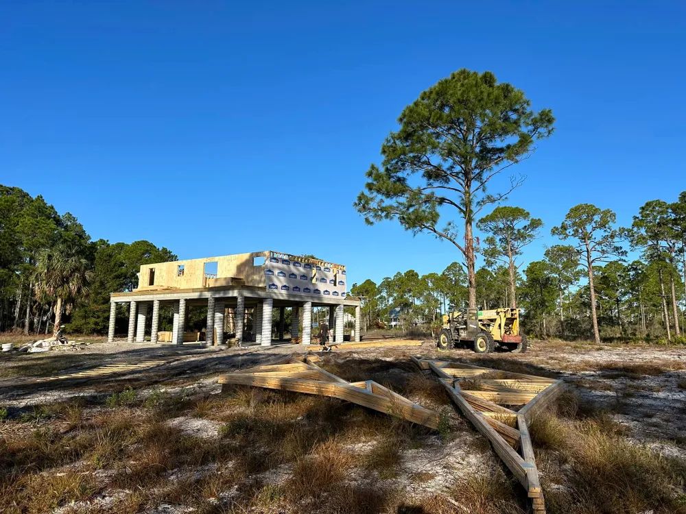 A house is being built in a field with trees in the background.