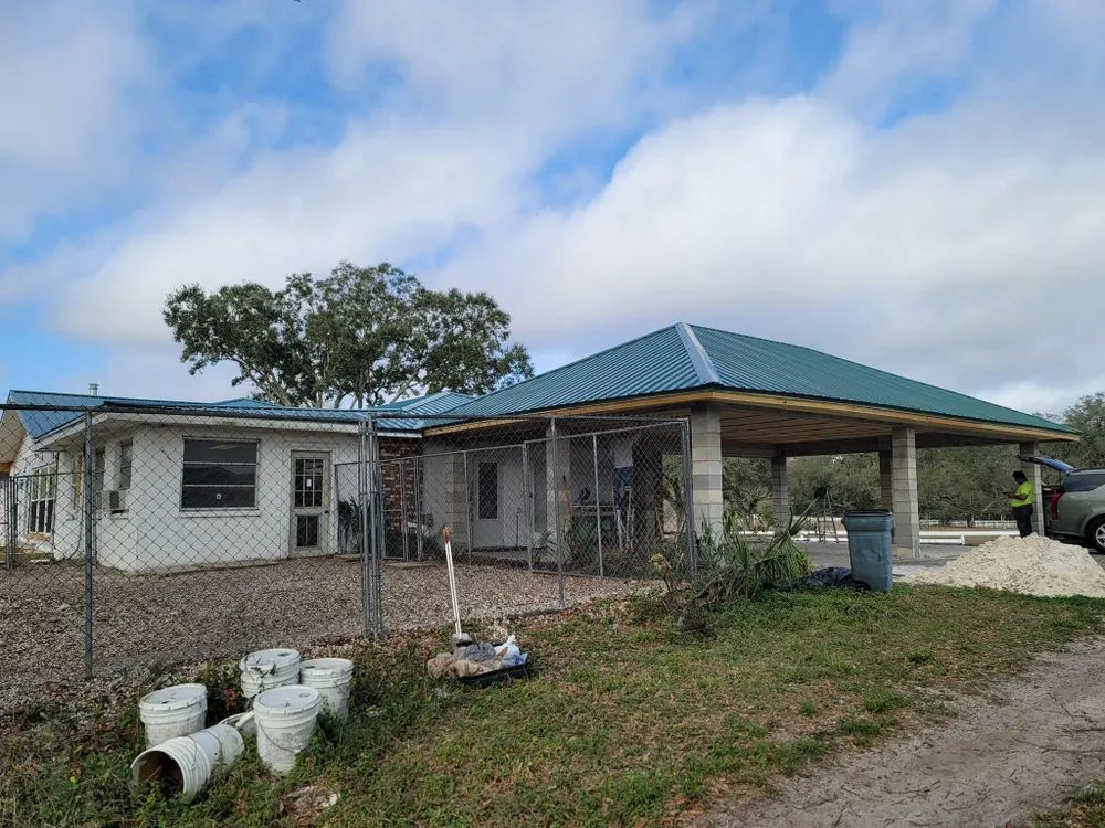 A white house with a green roof and a car parked in front of it.