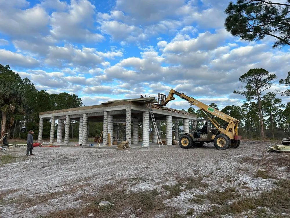 A construction site with a tractor and a forklift in front of a building under construction.
