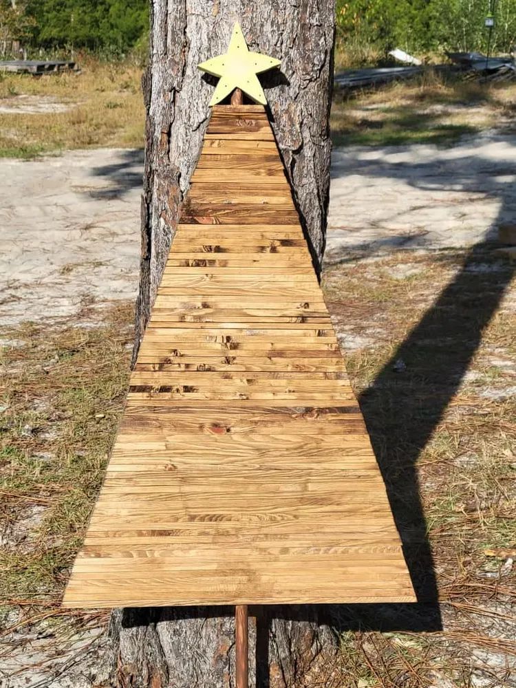 A wooden christmas tree made out of wooden pallets with a star on top.