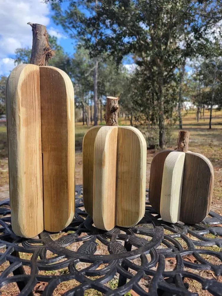 Three wooden pumpkins are sitting on top of a metal table.