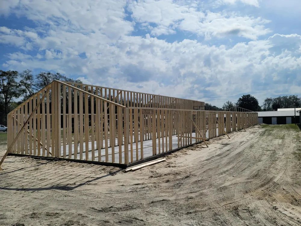 A large wooden structure is being built in a dirt field.