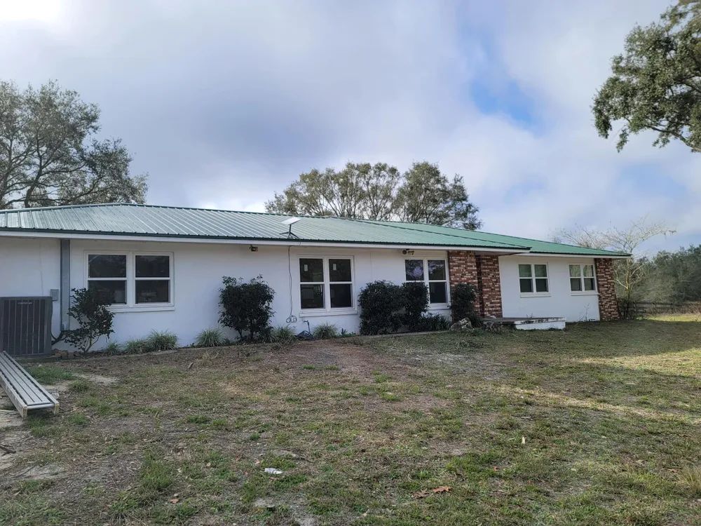 A white house with a green roof and a lot of windows