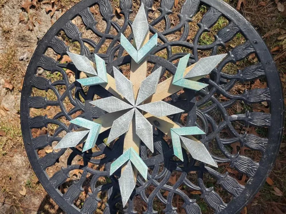 A wooden snowflake is sitting on top of a metal table.