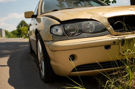 A damaged car is parked on the side of the road.