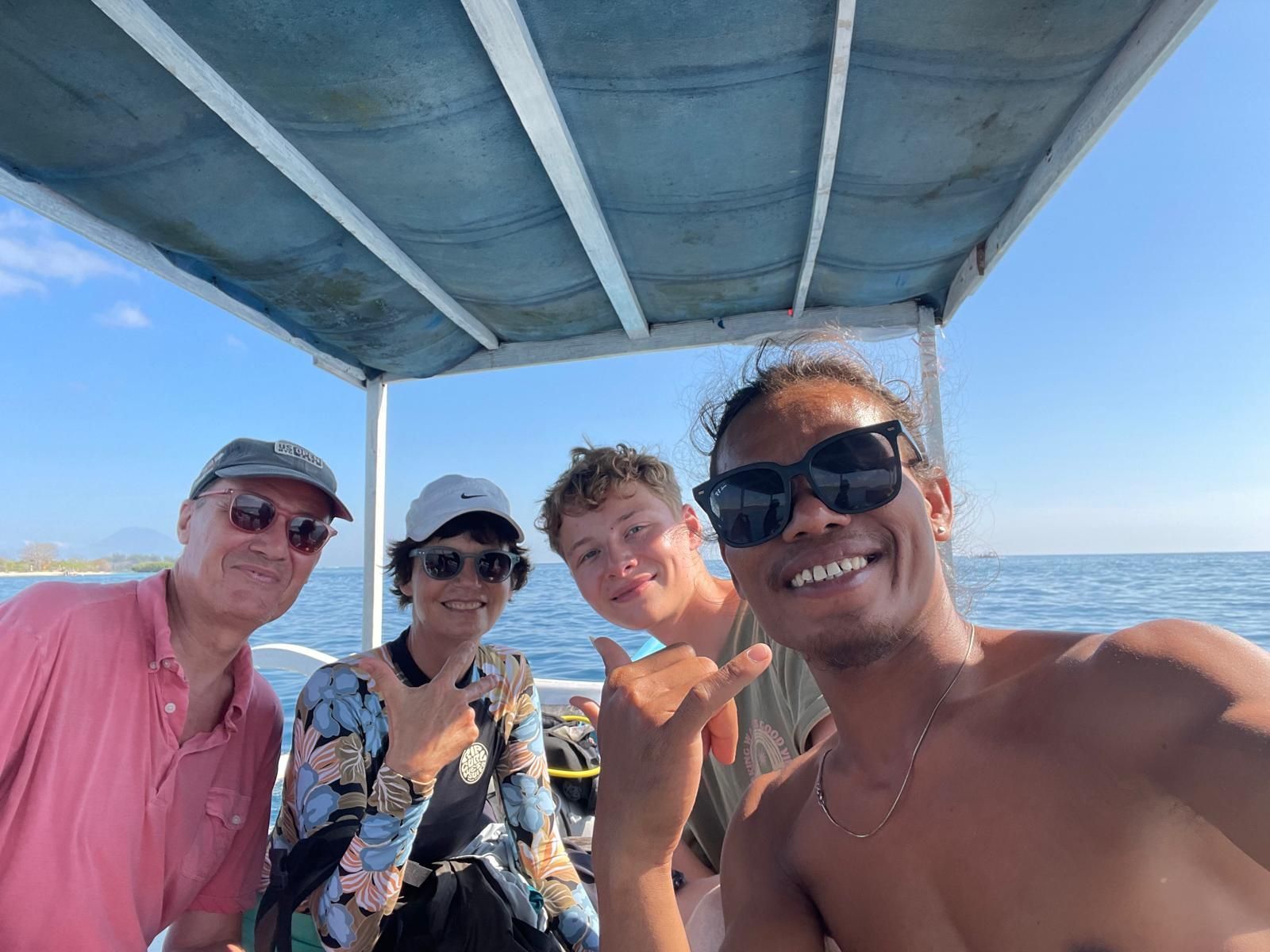 A group of people are posing for a picture on a boat in the ocean.