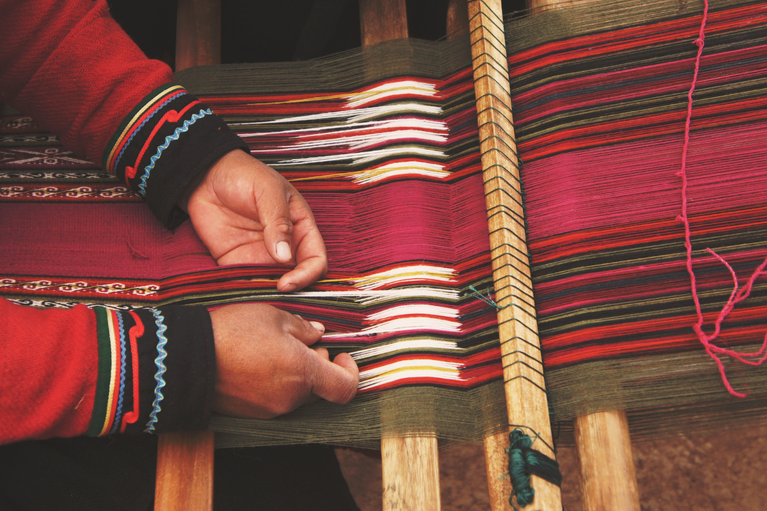 A person is weaving a blanket on a loom.