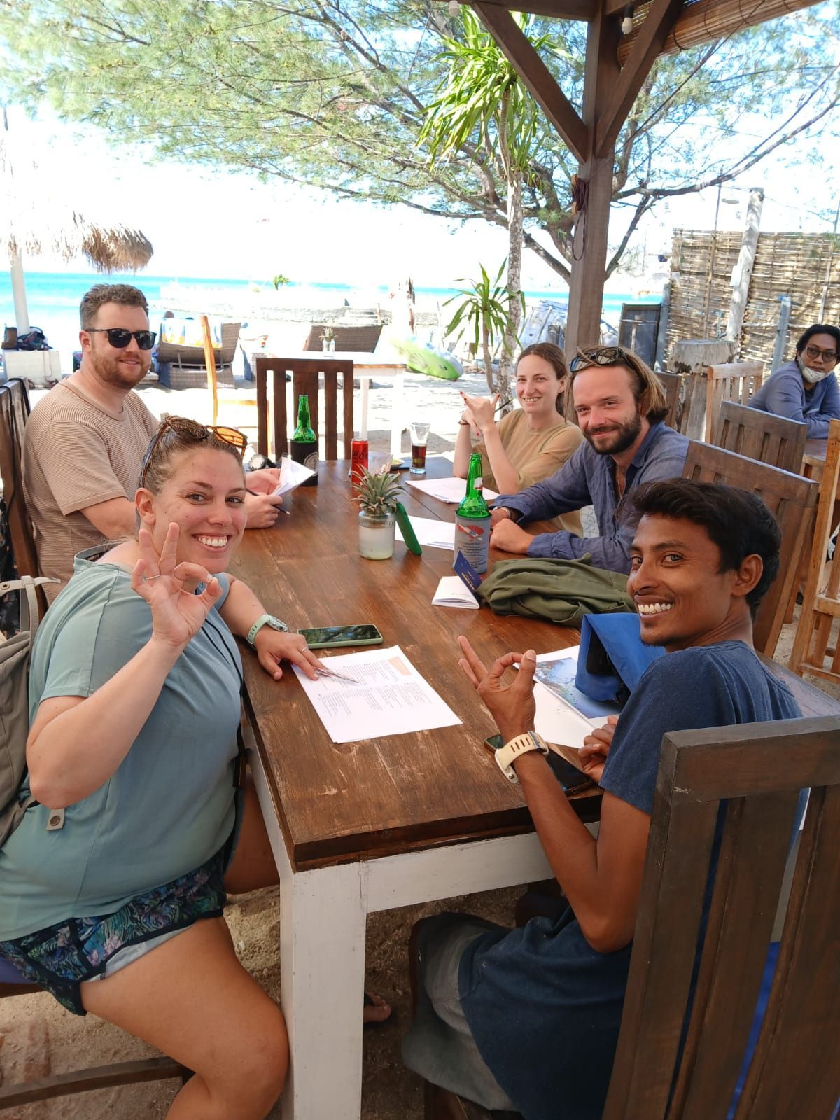 A group of people are sitting at a table in front of the ocean.