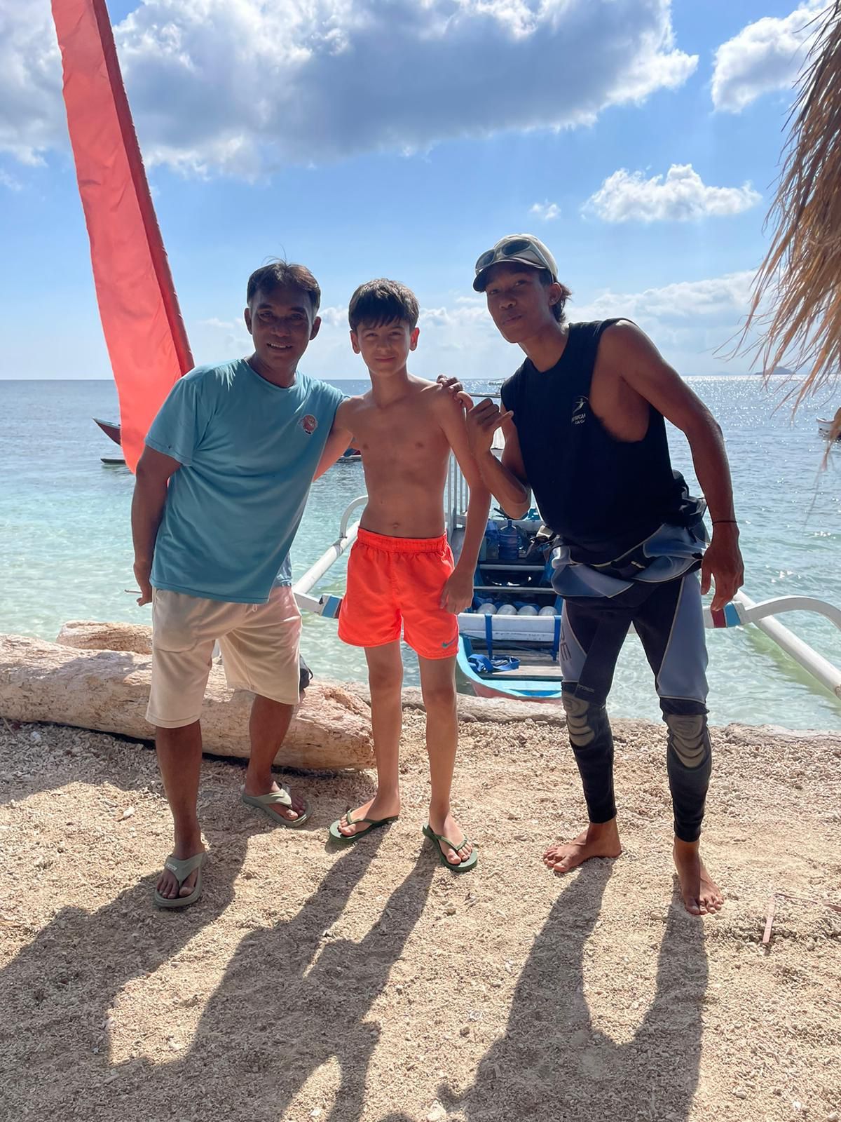 Three men are posing for a picture on the beach.