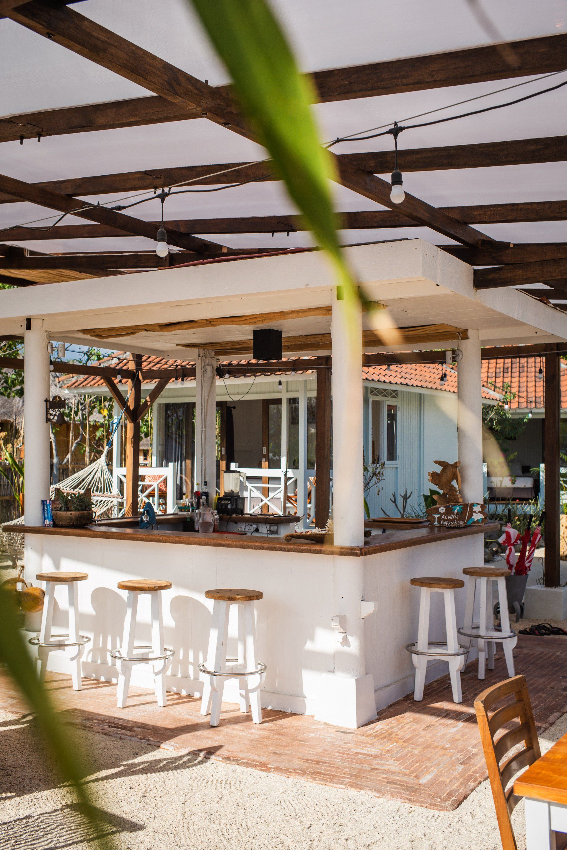 A restaurant with a bar and stools under a canopy.