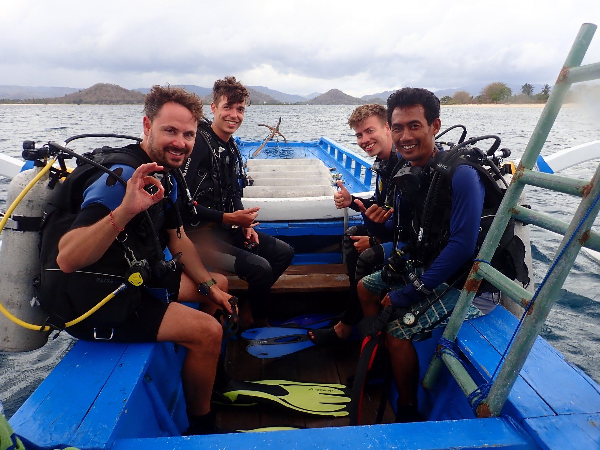 A group of scuba divers are sitting on a boat in the water.