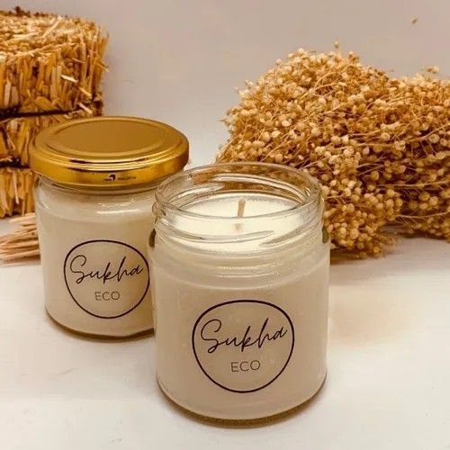 Dos velas Sukha Eco en frascos de vidrio con fondo decorativo de paja.