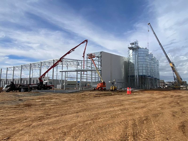 A Large Building Is Being Built in A Dirt Field — Maslin Concrete Pumping in Parkes, NSW