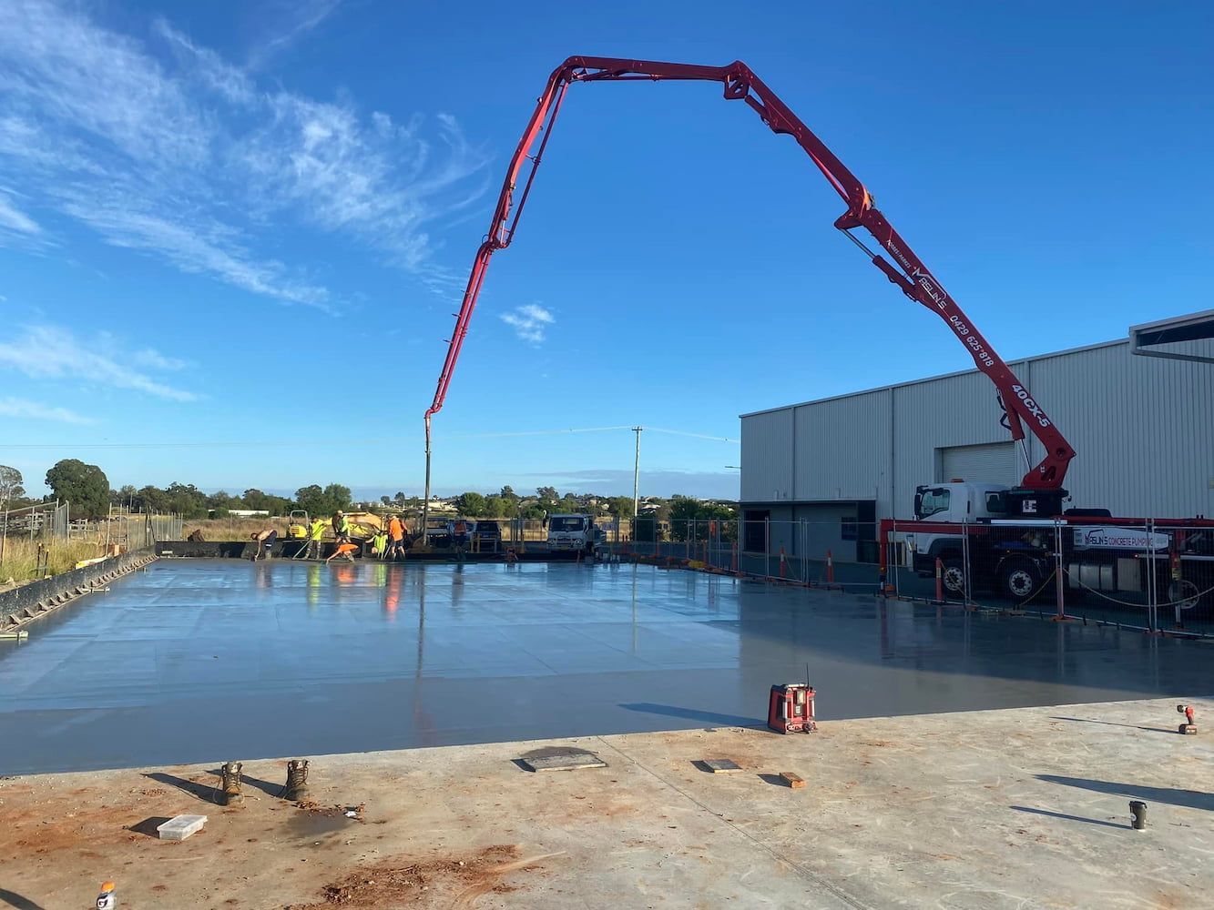 A Concrete Pump Is Being Used to Pour Concrete in Front of A Building — Maslin Concrete Pumping in West Wyalong, NSW