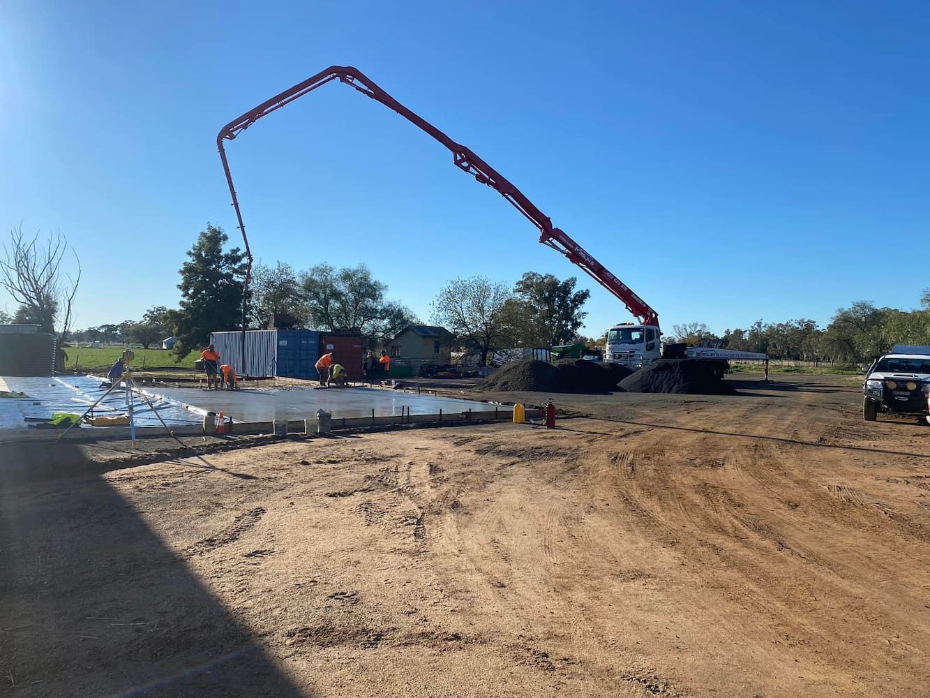 A Concrete Pump Is Being Used to Pour Concrete on A Dirt Road — Maslin Concrete Pumping in Forbes, NSW