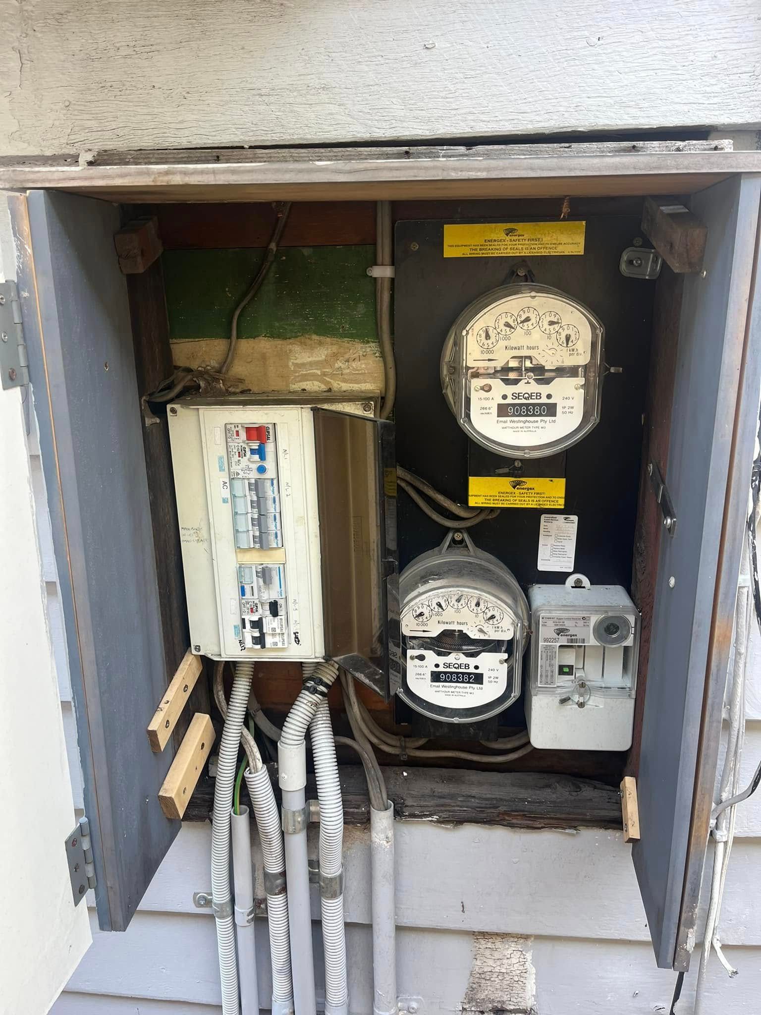An Open Outdoor Electrical Meter Box Containing Two Round Analog Meters — OHMY Electrical Contractors in Carina, QLD