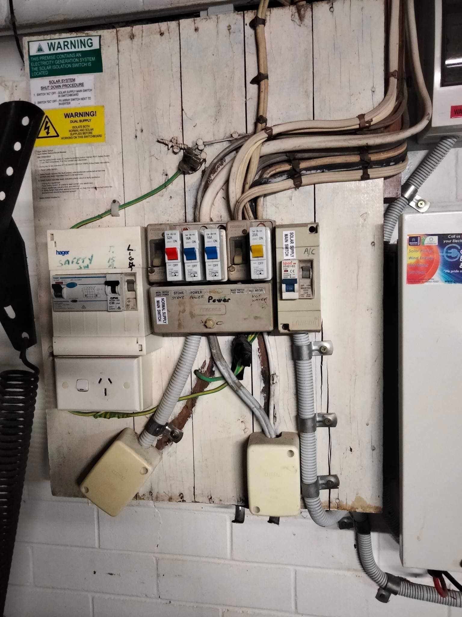 An Electrical Fuse Box Mounted on a White Wooden Board With Exposed Wiring — OHMY Electrical Contractors in Carina, QLD