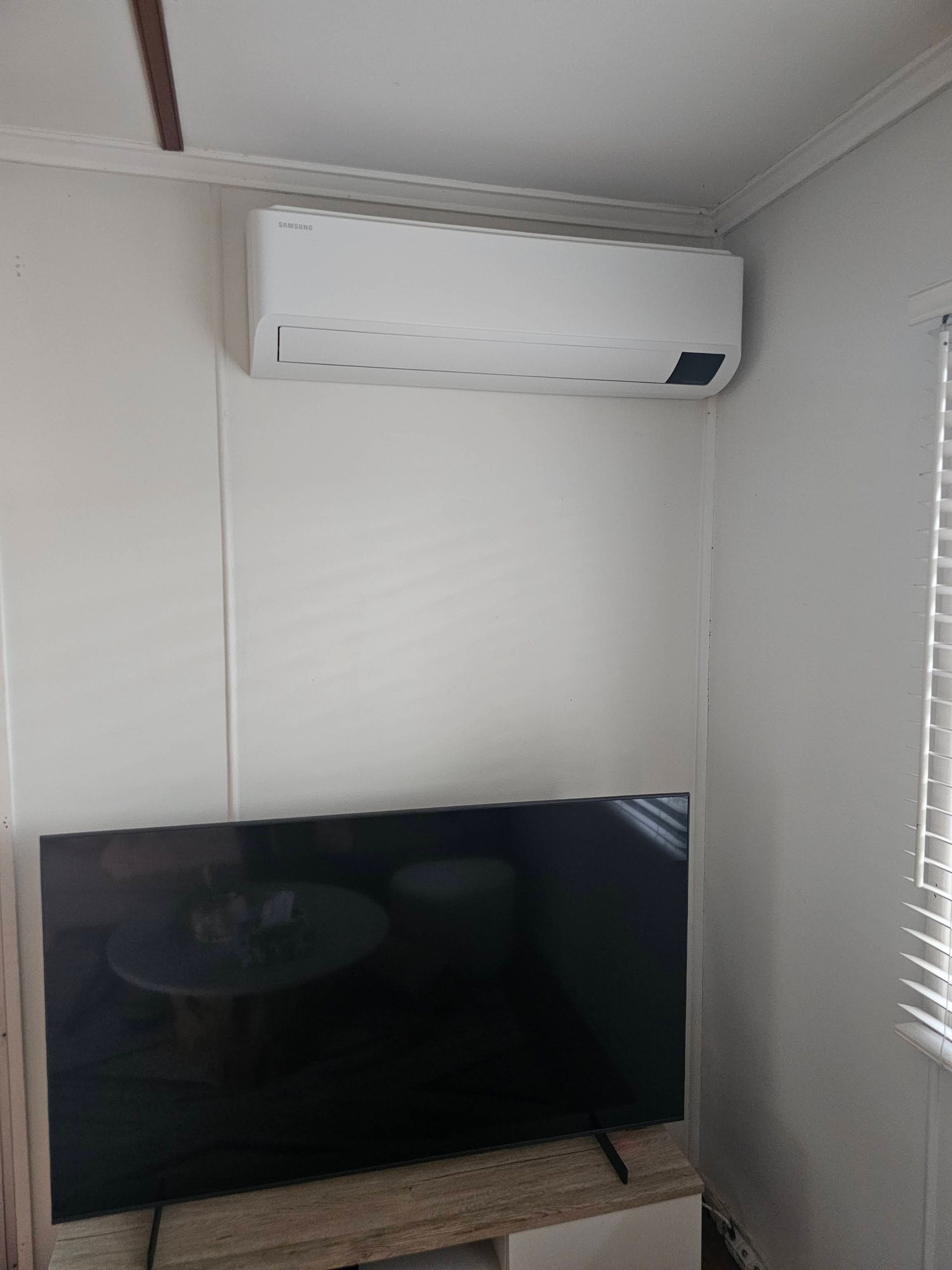 A White Wall-mounted AC Positioned Above a Large Flat-screen Television — OHMY Electrical Contractors in Carina, QLD