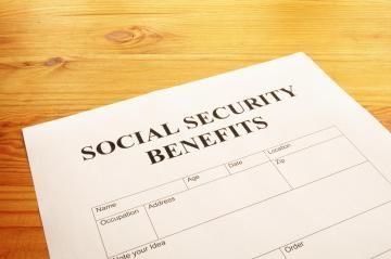 A blank Social Security benefits form rests on a light-colored wooden table.