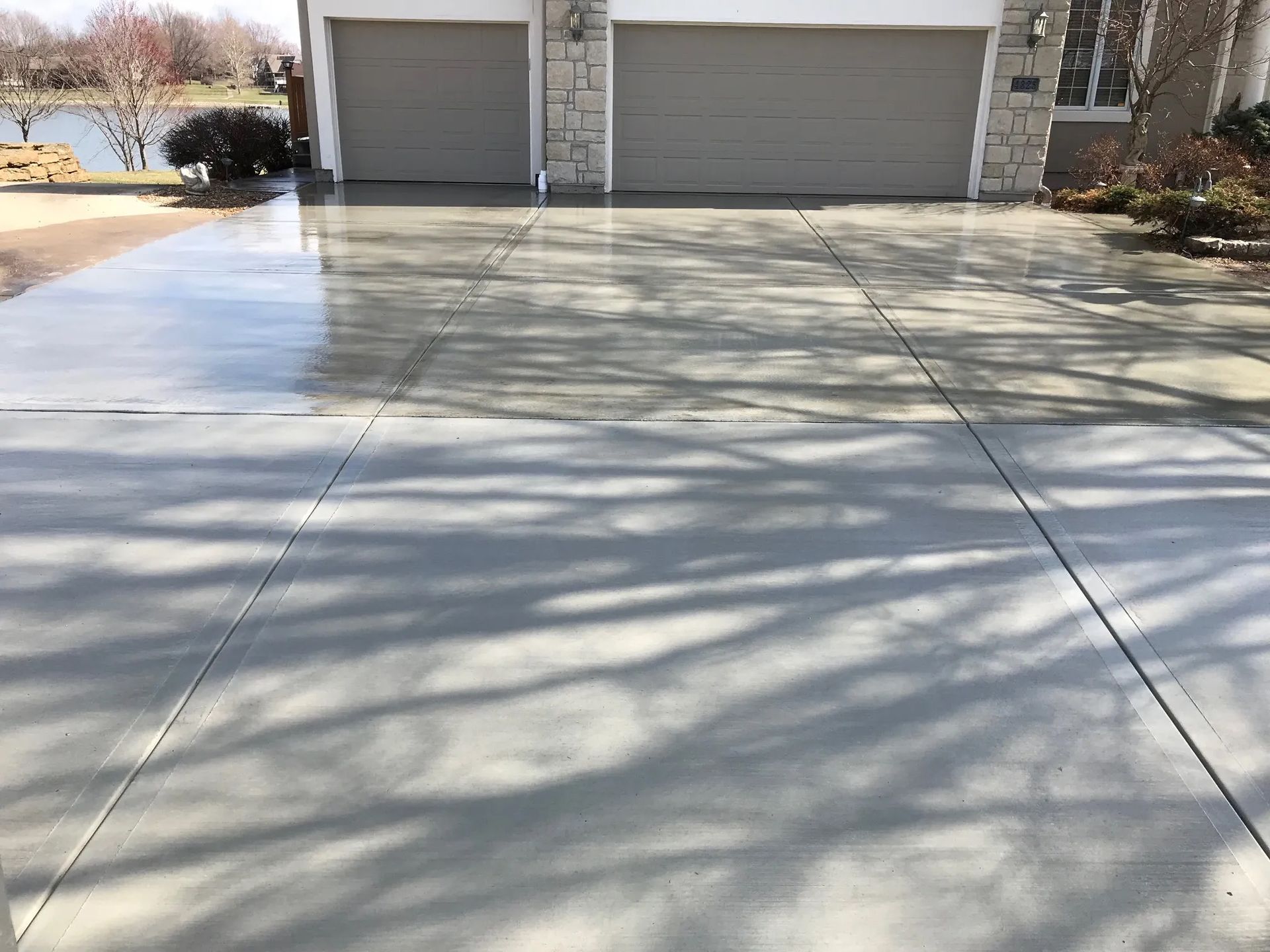 A person is using a broom to spread asphalt on a driveway.