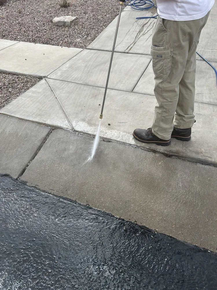 Person power washing a concrete sidewalk.