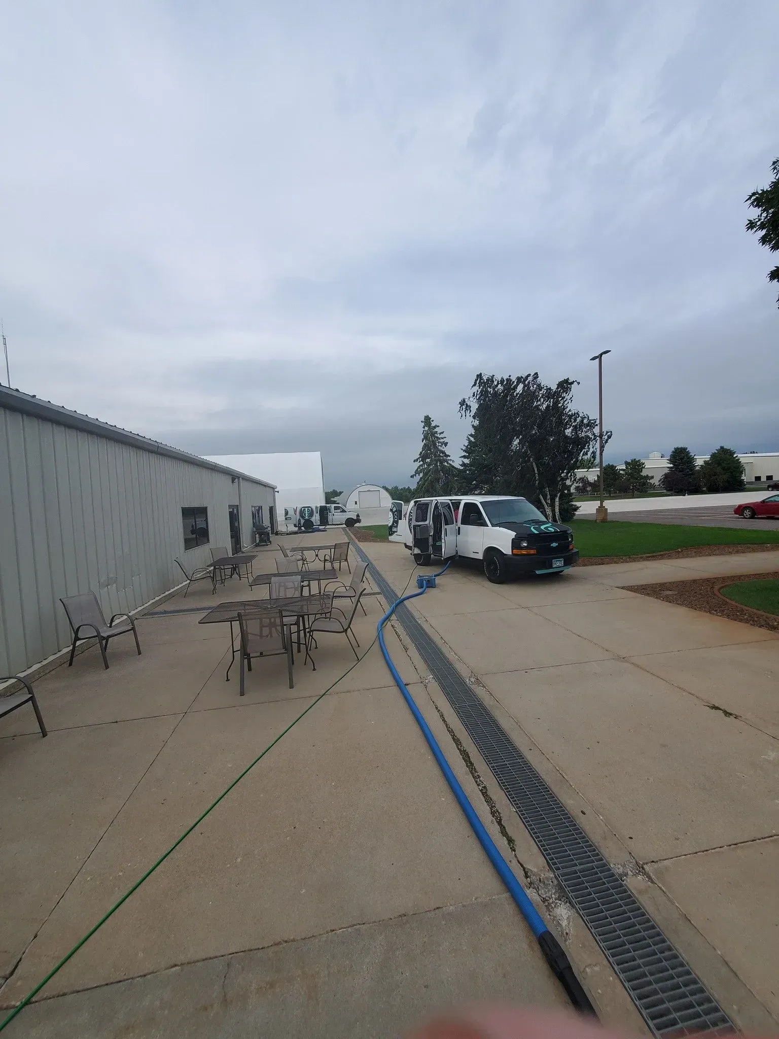 A white van is parked on the side of the road next to a hose.
