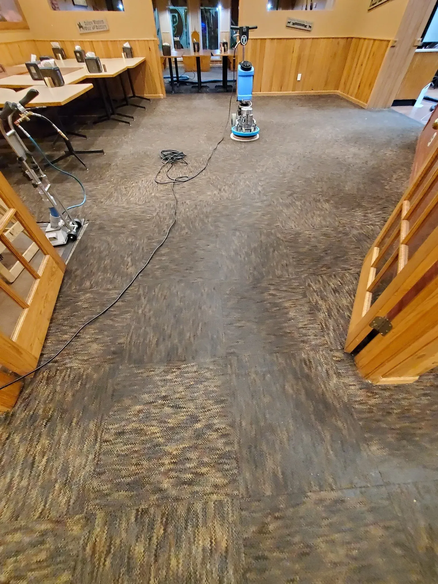 A vacuum cleaner is cleaning a carpeted floor in a room.