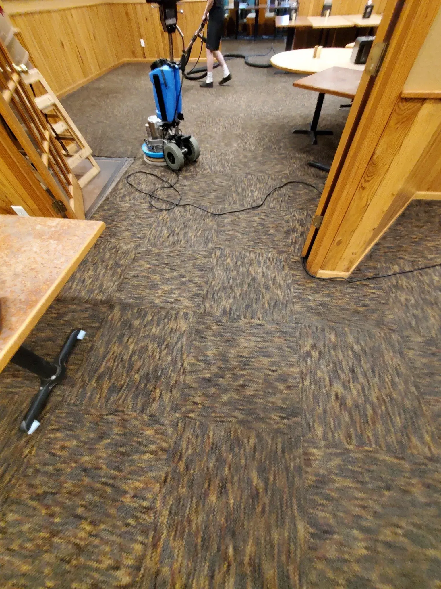 A person is vacuuming the floor of a restaurant.